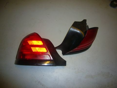 2000 Ford Crown Victoria - A damaged car taillight assembly is shown, with its red lens and black housing broken apart.
