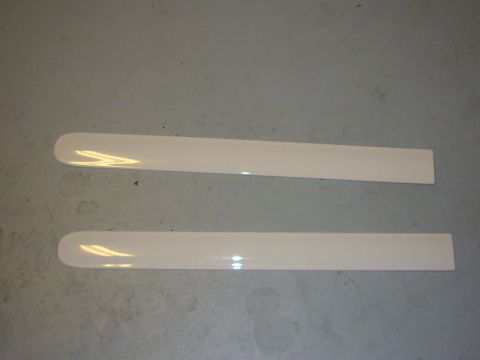 2000 Ford Crown Victoria - Two white trim pieces are shown lying on a gray, speckled floor.