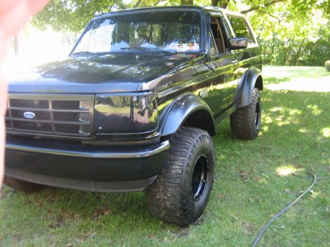 1995 Ford Bronco - This black Ford Bronco is shown from a three-quarter front angle, parked outdoors on a grassy lawn.