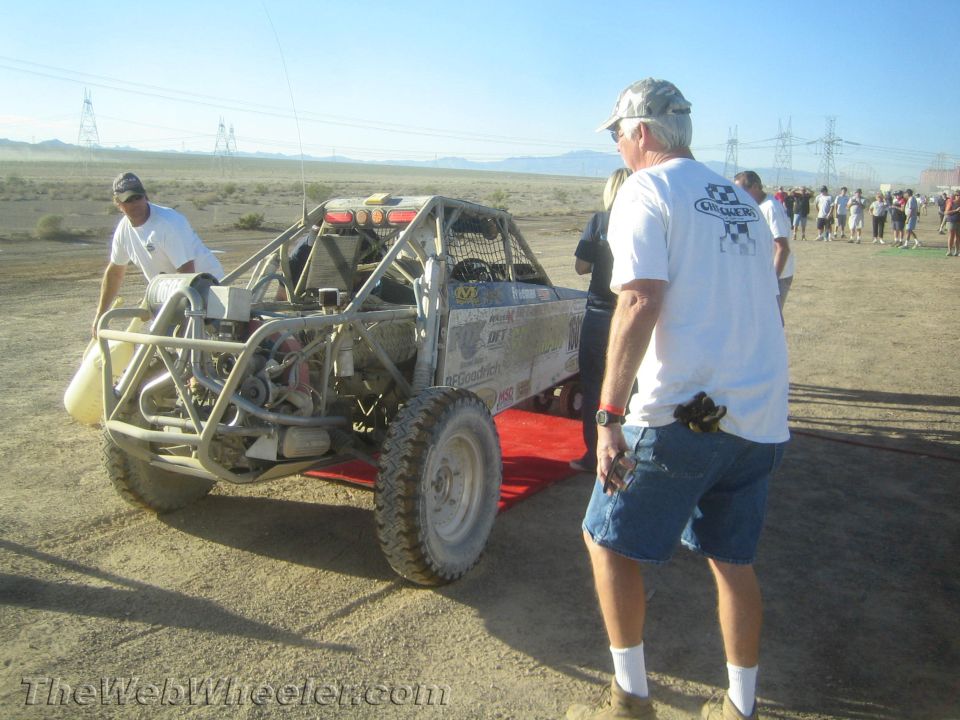 Rear of an off-road tube buggy with crew working on it in the desert