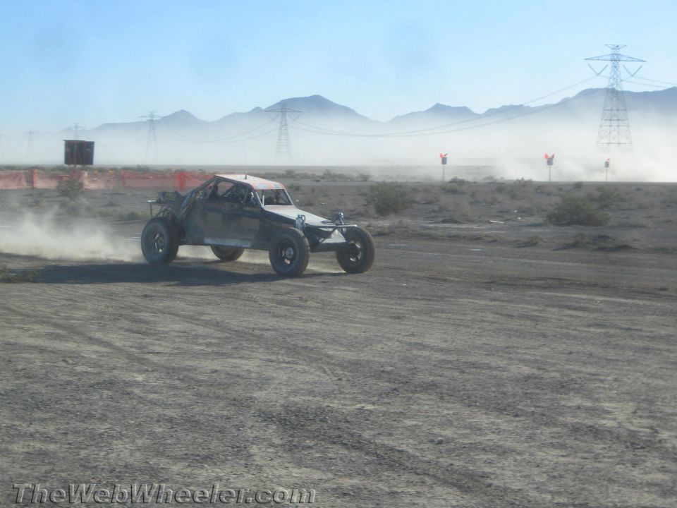 Off-road race buggy sliding through dust on a flat desert course