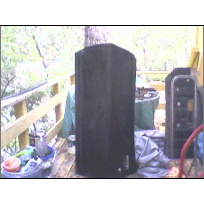 1973 Ford Ranchero - A black object, possibly a speaker or storage container, sits on a wooden deck surrounded by trees and various items.