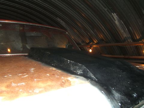 1980 Ford F-250 - A black hood scoop is installed on a vehicle's hood inside a corrugated metal building.