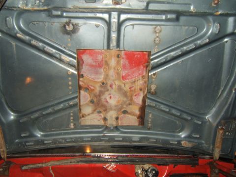 1980 Ford F-250 - The underside of a car hood shows a crude metal patch over rust damage.