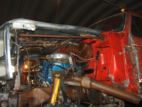 1980 Ford F-250 - The engine compartment of a truck shows a blue engine, exhaust system, and red bodywork, indicating it's undergoing work.