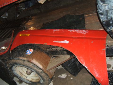 1980 Ford F-250 - Close-up of a red fender and wheel, a P logo and visible rust, suggesting it's a replacement part.