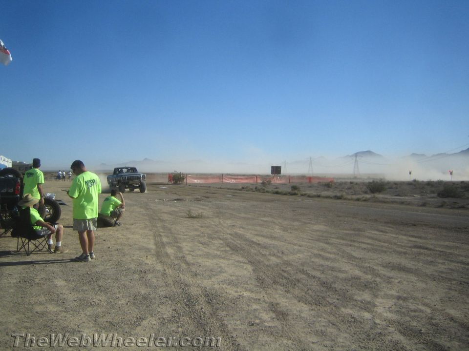 Blue and white pickup driving on a dusty desert off-road course