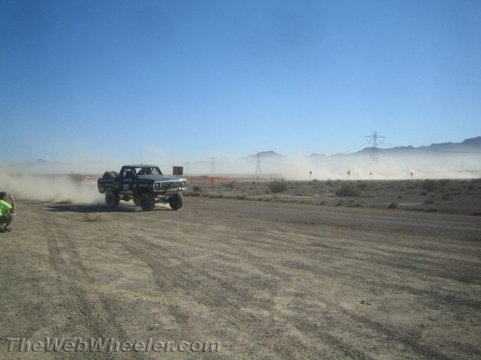 Numbered off-road race truck speeding through desert dust