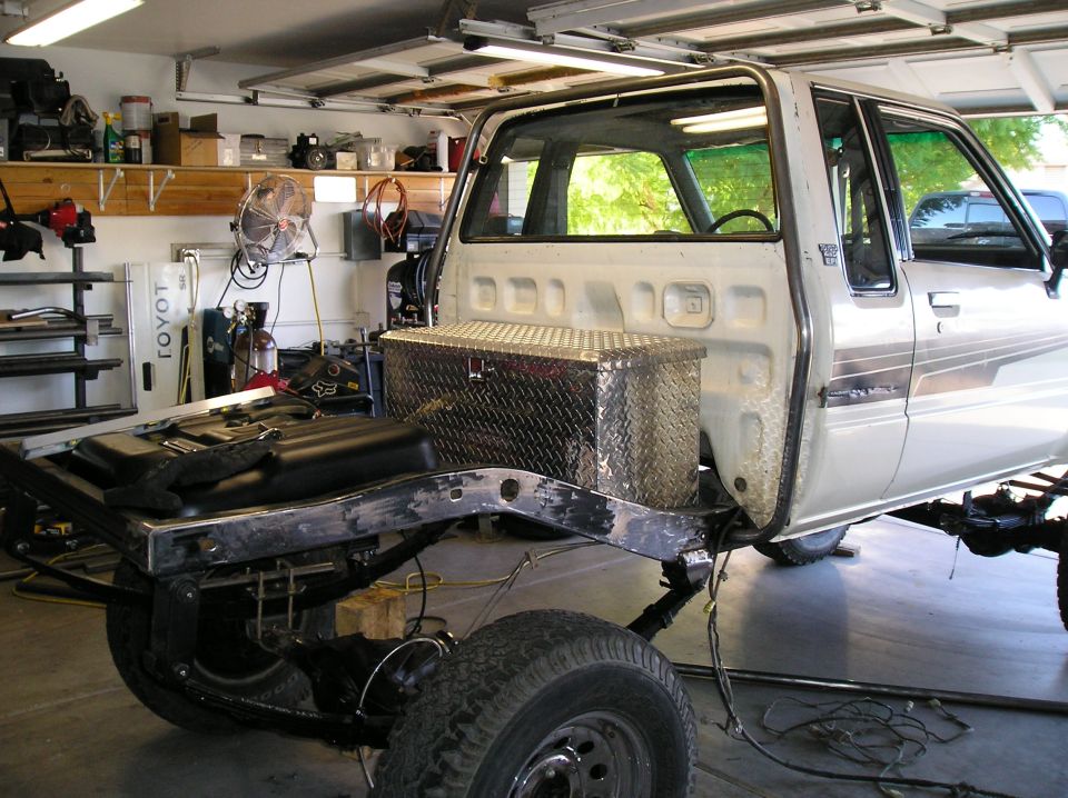 Toyota pickup cab and bare frame in a garage during a body-off restoration