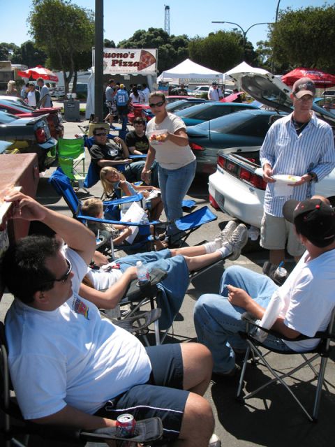 1995 Ford Probe - Attendees relax at an outdoor car event, with food vendors and multiple vehicles present.