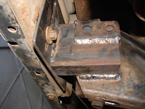 1973 Ford Ranchero - Close-up of a custom-fabricated steel bracket joined to a rusty frame member with fresh MIG weld beads, with a large hex bolt through the a…