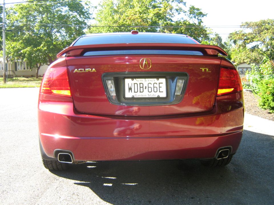Red Acura TL sedan rear view, showing taillights, spoiler, and license plate WDB-66E