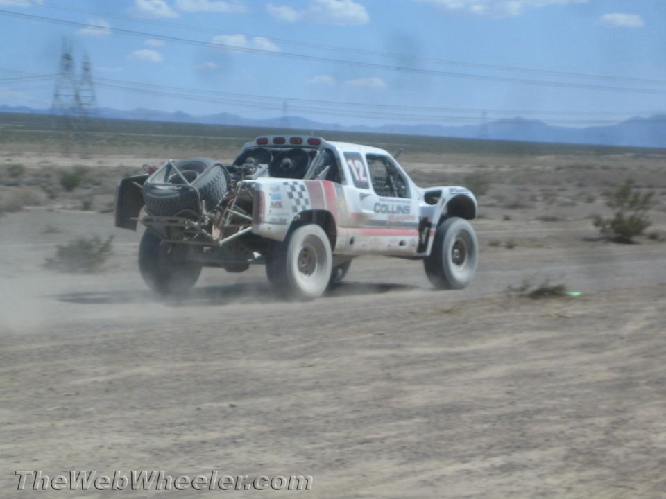 White Collins off-road race truck racing through the open desert