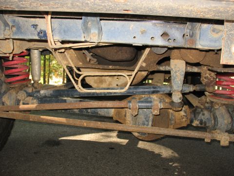 1995 Ford C-350 (Centurion Conversions) - The underside of a vehicle reveals its suspension system, including shocks, springs, and steering linkage.
