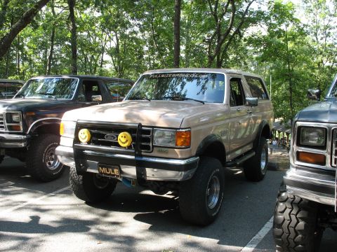 1995 Ford C-350 (Centurion Conversions) - Tan Ford Bronco parked next to other trucks, custom grille lights and a "MULE" plate.