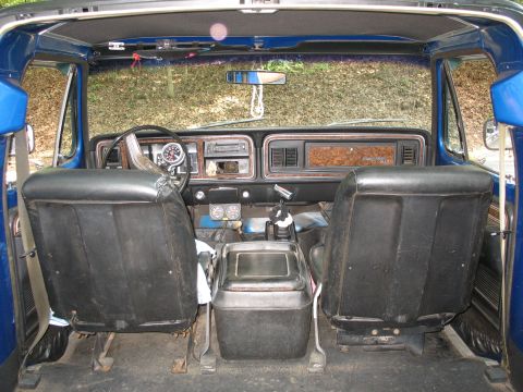 1995 Ford C-350 (Centurion Conversions) - The interior of a blue truck shows a dashboard with woodgrain trim and aftermarket gauges, along with black vinyl seats.