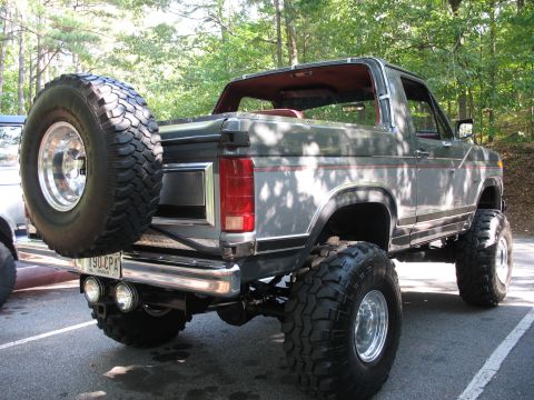 1995 Ford C-350 (Centurion Conversions) - Rear view of a lifted gray Ford Bronco with a spare tire mounted externally.