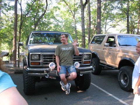 1995 Ford C-350 (Centurion Conversions) - Two lifted Ford Broncos are parked outdoors with trees in the background.