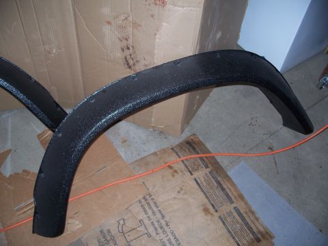 1979 Ford F-150 - Two black textured fender flares are shown, with cardboard boxes and an orange cord in the background.