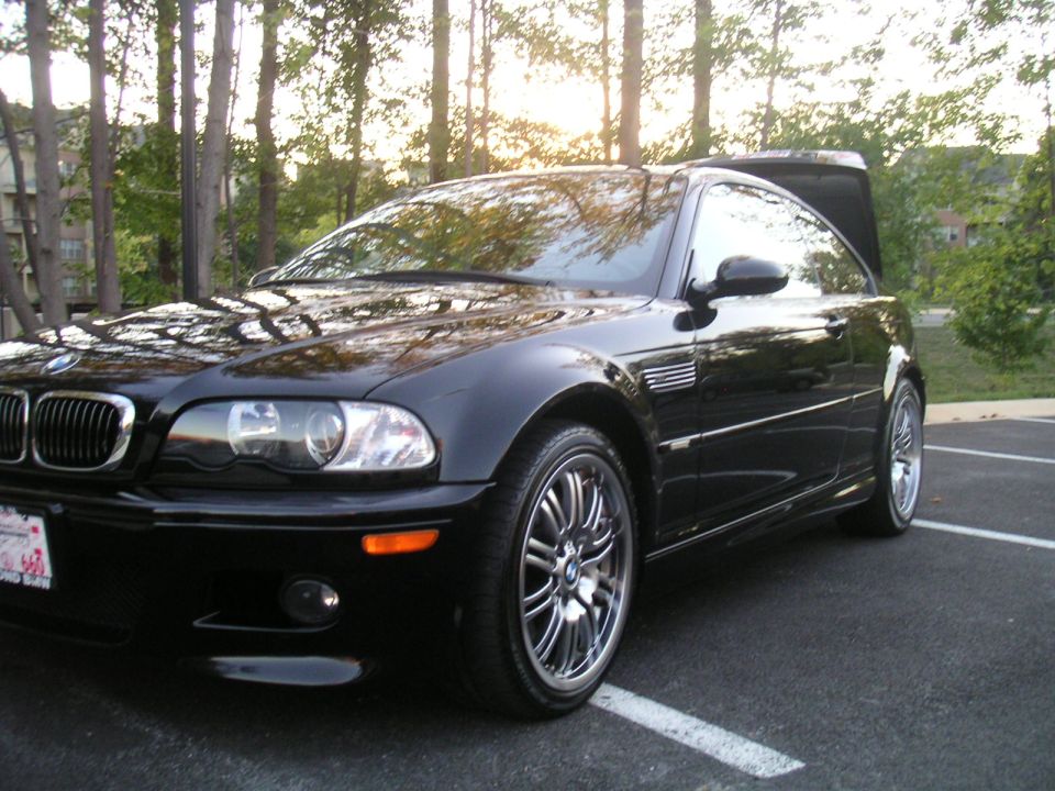 Black 2002 BMW M3 coupe parked in a lot, front 3/4 view, trunk open