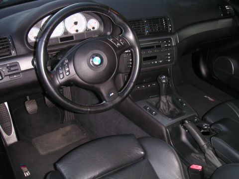 2002 BMW M3 - The interior of a 2002 BMW M3 features a leather-wrapped steering wheel and a manual transmission, indicating a driver-focused experience.