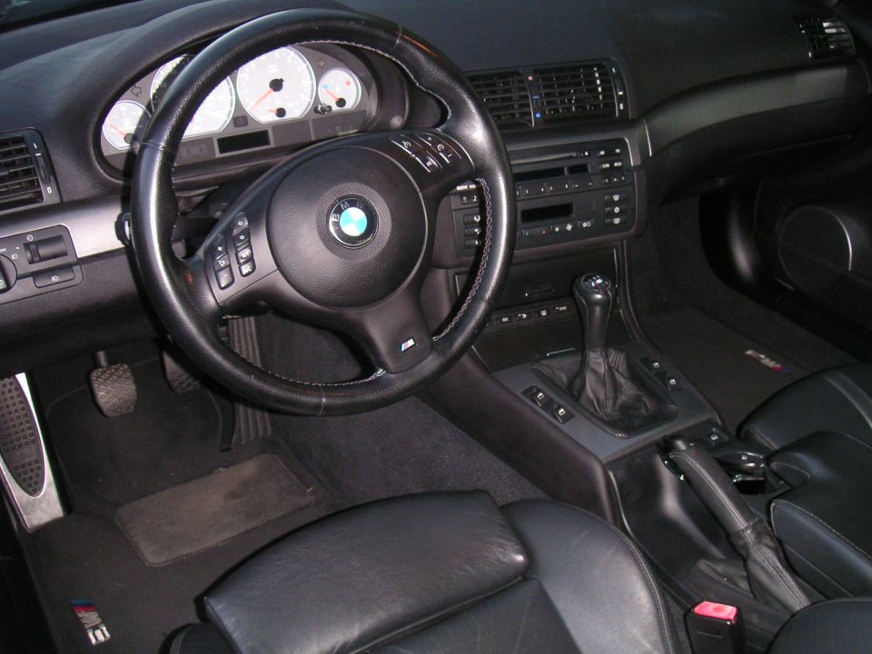 Interior of a 2002 BMW M3 showing dashboard, steering wheel, and manual shifter