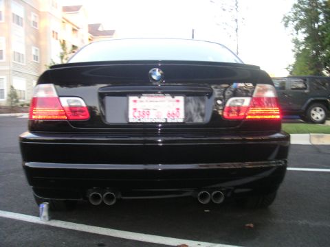 2002 BMW M3 - The rear of a black BMW M3 sedan is shown, its distinctive taillights and quad exhaust tips.