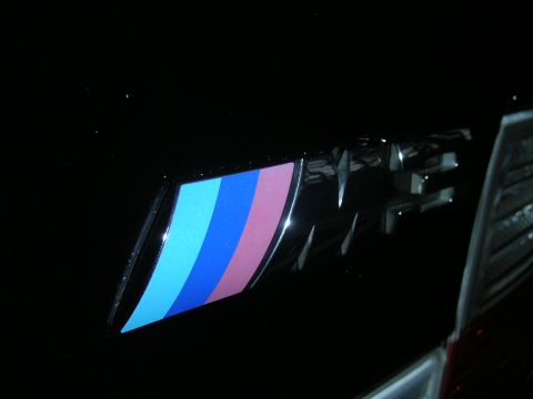 2002 BMW M3 - Close-up of a black BMW M badge with its signature tri-color stripes.