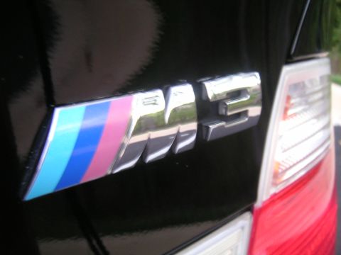 2002 BMW M3 - Chrome M3 badge with BMW M stripes on a black car's rear.