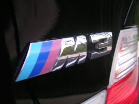 2002 BMW M3 - A close-up shot of the M3 emblem on a black car, showing the iconic M stripes.