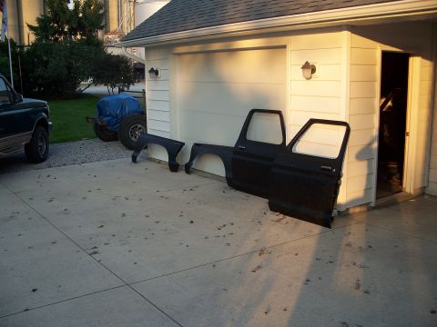 1979 Ford F-150 - Black truck doors and fenders are disassembled and placed on a concrete driveway next to a garage.