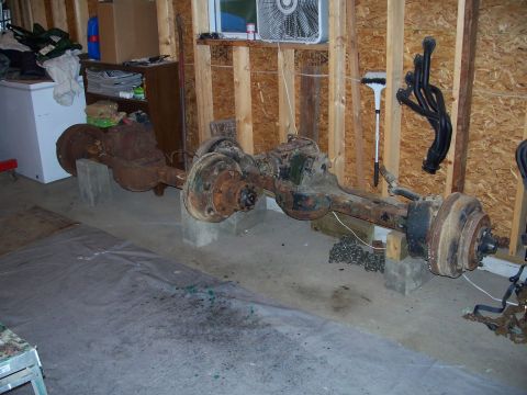 1979 Ford F-150 - Two old truck axles are stored in a garage, awaiting restoration or replacement.