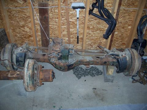 1979 Ford F-150 - A heavily rusted rear axle assembly, likely from an older truck, is stored in an attic space.