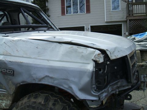 1995 Ford Bronco - This 1995 Ford Bronco shows significant front-end damage, including a crumpled hood and fender, with a visible roll cage.