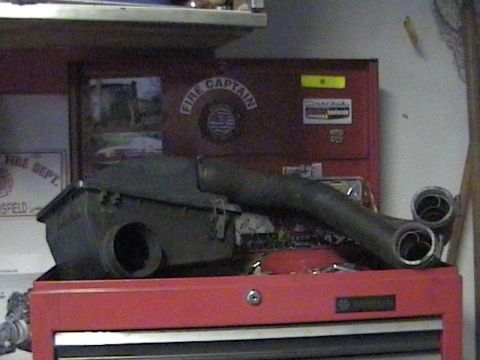 1990 Ford Bronco - Exhaust manifold and air intake box resting on a red toolbox in a garage.