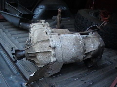 1990 Ford Bronco - A heavy-duty transfer case is loaded into the bed of a pickup truck alongside a spare tire.