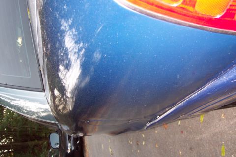 2001 Ford Crown Victoria - Close-up of a blue car's rear quarter panel and taillight, showing reflections.