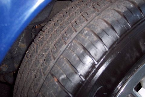 2001 Ford Crown Victoria - Close-up view of a vehicle's tire and the surrounding wheel well area.