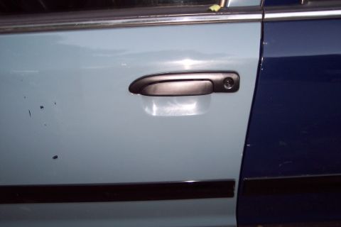 2001 Ford Crown Victoria - The car door handle is black and mounted on a light blue door panel. The adjacent door is dark blue.