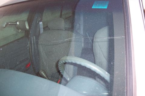 2001 Ford Crown Victoria - Interior view of a dusty 2001 Ford Crown Victoria, showing gray seats and a cracked windshield.