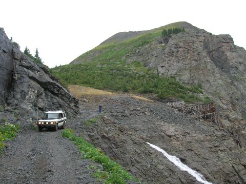 1999 Land Rover Discovery II - A white 1999 Land Rover Discovery II navigates a narrow, rocky mountain pass with a person standing on the slope.