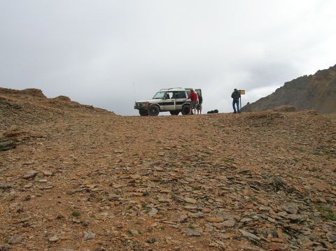 1999 Land Rover Discovery II - Two SUVs are parked on a rocky incline under an overcast sky, with several people nearby.