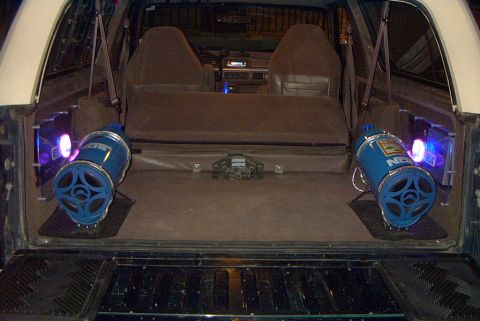 1992 Ford Bronco - The rear interior of a vehicle is shown, two large blue speakers with blue and purple lighting effects.