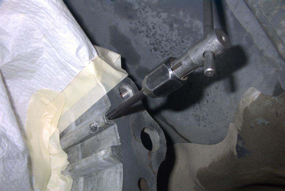 Metal linkage joint and rod under a vehicle with masking tape nearby