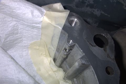1992 Ford Bronco - A metal engine component, possibly part of a pump fix, is covered with tape and paper towels for protection.