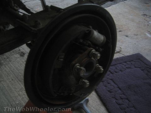 1987 Suzuki Samurai - The rear axle brake drum assembly is shown with the brake cylinder and lug nuts.