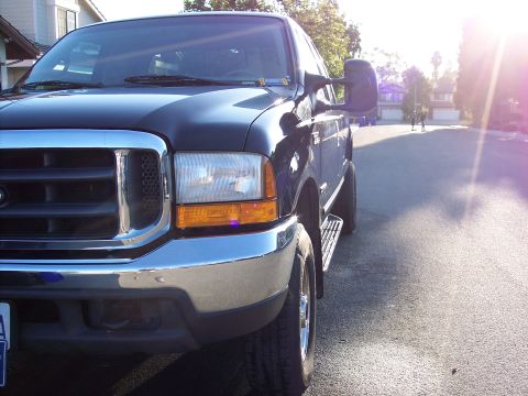 2000 Ford F-250 - A dark blue 2000 Ford F-250 truck is parked on a residential street during a sunny day.
