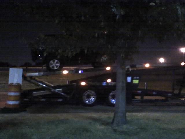 Dark SUV parked behind a car trailer at night