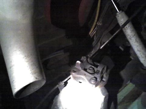 1992 Ford Bronco - Close-up view of vehicle undercarriage components, including an exhaust pipe and shock absorber.