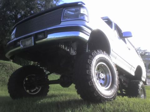 1995 Ford Bronco - This modified 1995 Ford Bronco features a significant lift kit and aggressive off-road tires, giving it a commanding presence.